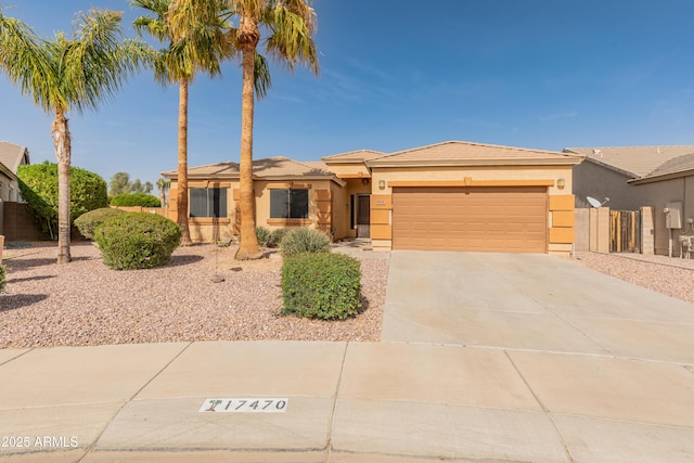 view of front facade featuring a garage, concrete driveway, fence, and stucco siding