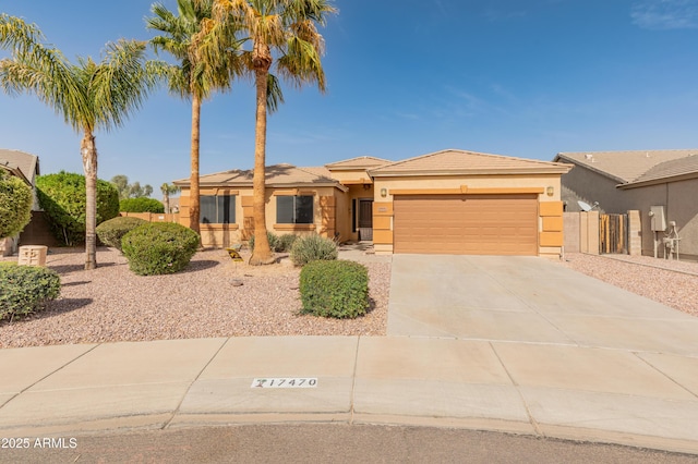 view of front facade with an attached garage, driveway, fence, and stucco siding