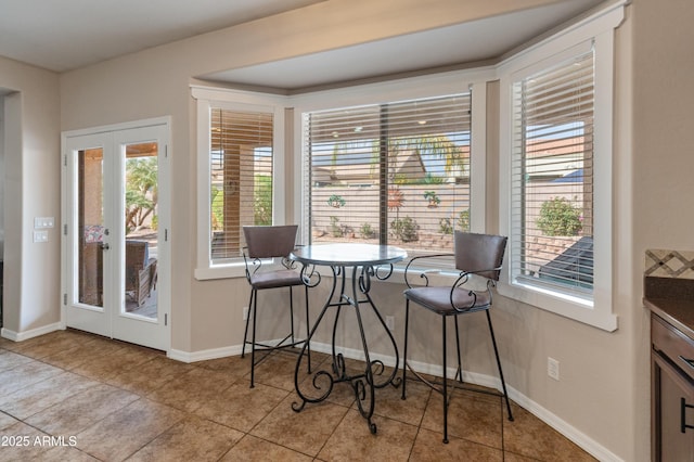 tiled dining area featuring french doors and baseboards