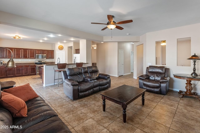 living area featuring light tile patterned flooring, ceiling fan, and baseboards