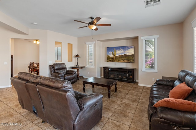 living room with ceiling fan, light tile patterned flooring, a fireplace, visible vents, and baseboards