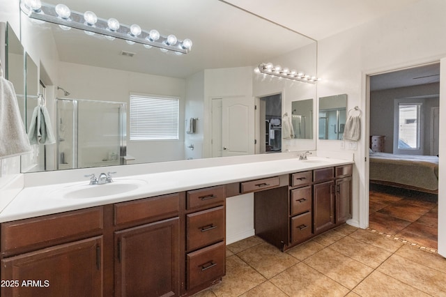 ensuite bathroom featuring double vanity, a stall shower, tile patterned flooring, and a sink