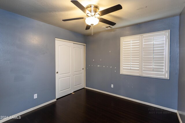 unfurnished bedroom featuring ceiling fan, a closet, and dark hardwood / wood-style flooring