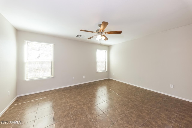 unfurnished room featuring a ceiling fan, dark tile patterned flooring, visible vents, and baseboards