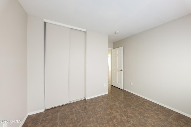 unfurnished bedroom with a closet and baseboards