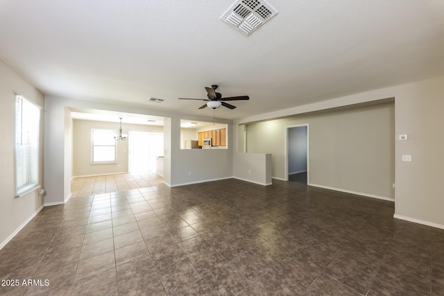 empty room with dark tile patterned flooring, visible vents, baseboards, and ceiling fan with notable chandelier