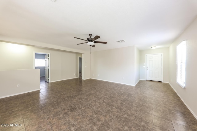 unfurnished room with baseboards, visible vents, and a ceiling fan