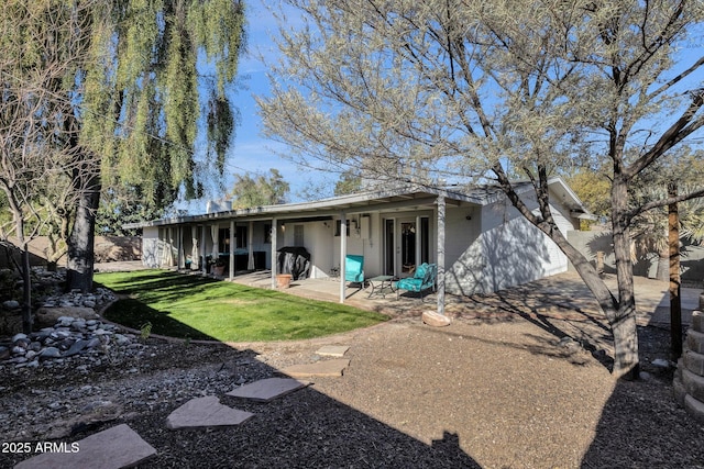 back of property with a lawn and a patio area