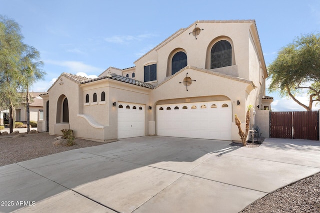 mediterranean / spanish-style home featuring driveway, a garage, a tile roof, fence, and stucco siding