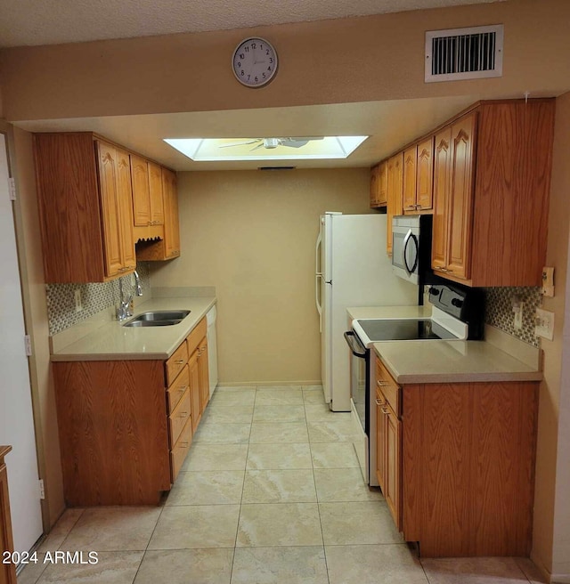 kitchen featuring backsplash, a skylight, sink, range with electric stovetop, and light tile patterned flooring