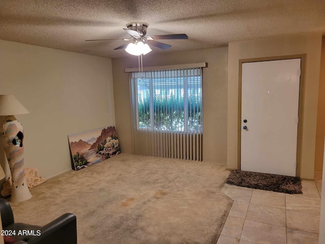 foyer entrance featuring a textured ceiling, carpet floors, and ceiling fan