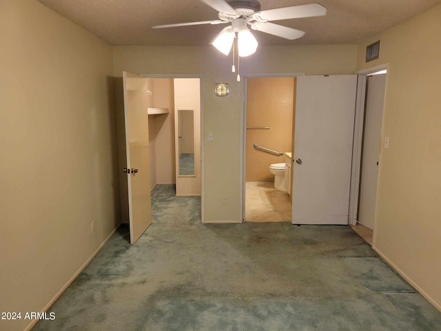 unfurnished bedroom with light carpet, a textured ceiling, ensuite bath, and ceiling fan