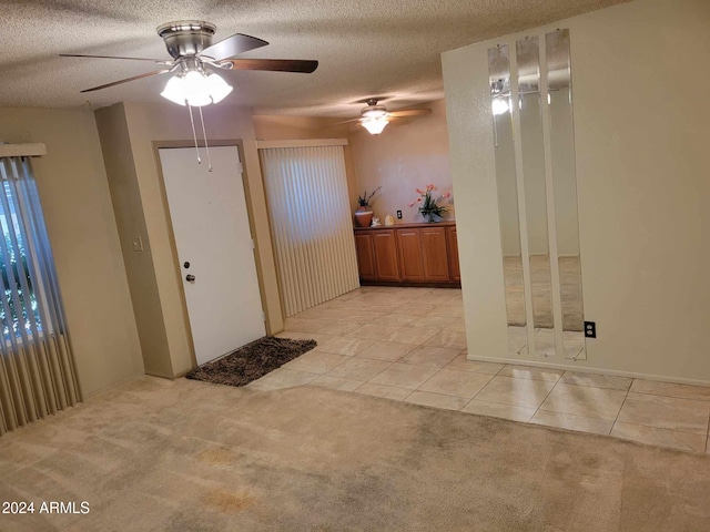 interior space featuring ceiling fan, light colored carpet, and a textured ceiling