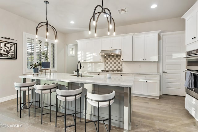 kitchen featuring hanging light fixtures, appliances with stainless steel finishes, and white cabinets