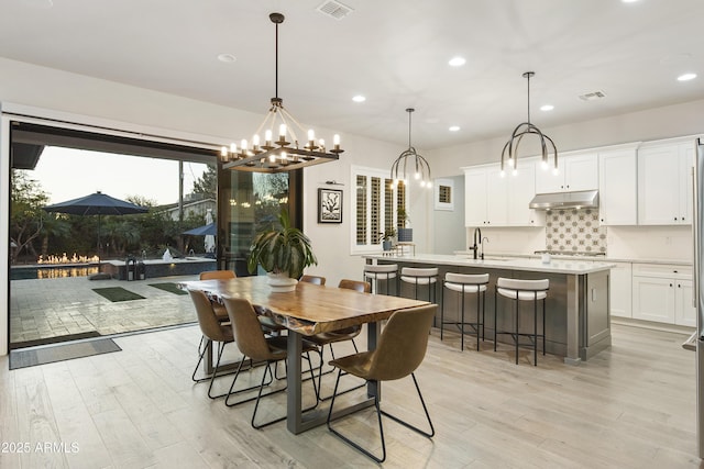 dining room featuring sink, a fireplace, and light hardwood / wood-style floors