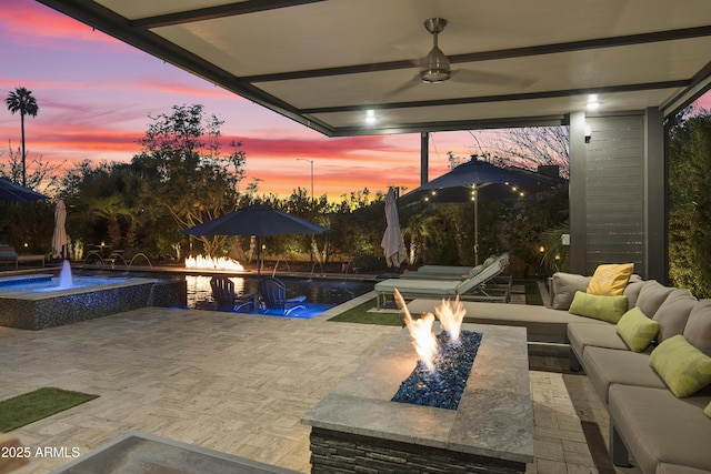 patio terrace at dusk featuring pool water feature and an outdoor living space with a fire pit