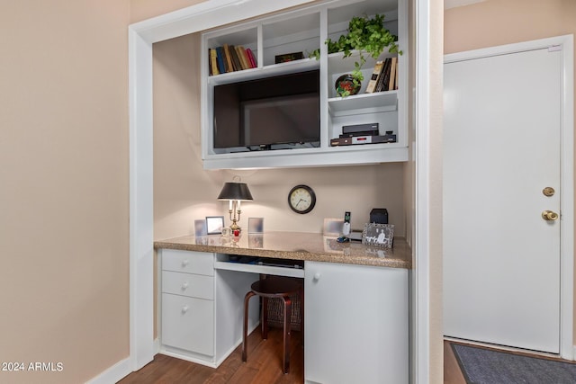 bar featuring white cabinetry, built in desk, and hardwood / wood-style floors