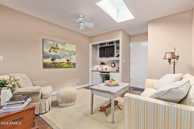 living room with hardwood / wood-style flooring, ceiling fan, and vaulted ceiling with skylight