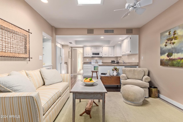 living room with ceiling fan, sink, and light hardwood / wood-style flooring