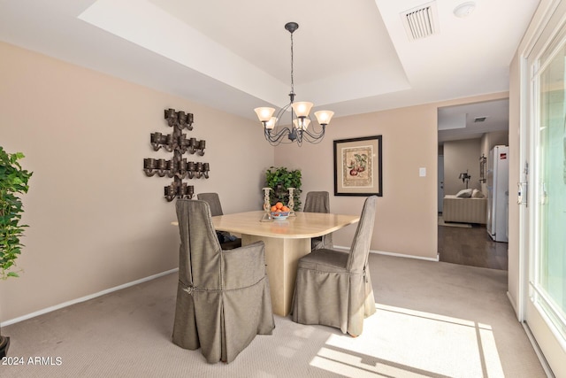 dining space featuring an inviting chandelier, light colored carpet, and a raised ceiling