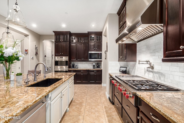 kitchen with wall chimney exhaust hood, tasteful backsplash, sink, appliances with stainless steel finishes, and white cabinetry