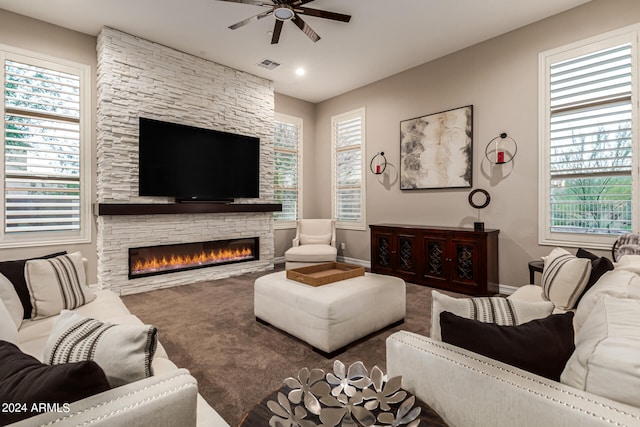 living room with ceiling fan, a wealth of natural light, and a stone fireplace