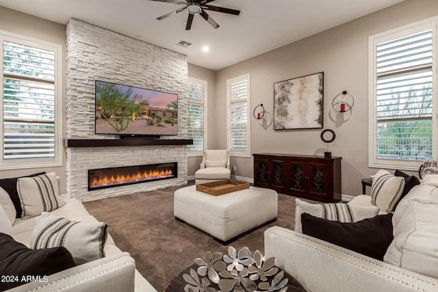 living room featuring ceiling fan and a stone fireplace