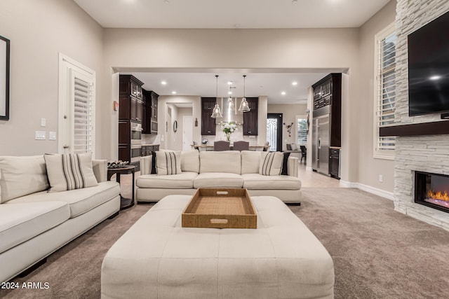 living room with carpet floors and a stone fireplace