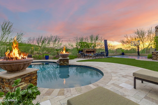 pool at dusk with a jacuzzi, a patio, and an outdoor fire pit