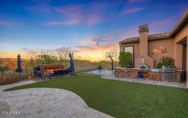 yard at dusk with exterior kitchen and a patio