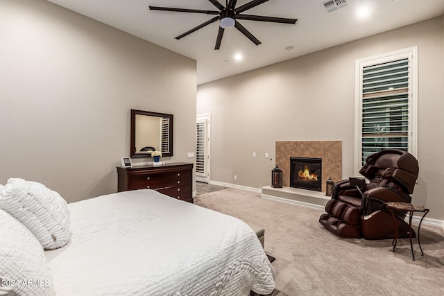 bedroom with a fireplace, light colored carpet, and ceiling fan