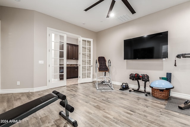 workout room featuring french doors, light hardwood / wood-style flooring, and ceiling fan