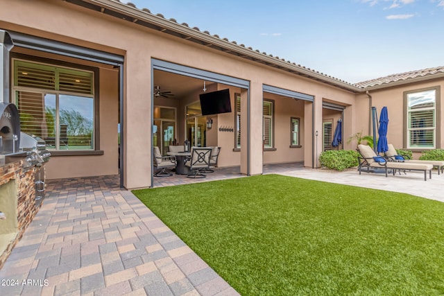 back of property featuring exterior kitchen, a yard, a patio area, and ceiling fan