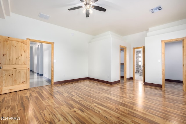 unfurnished bedroom with ensuite bathroom, a walk in closet, a closet, hardwood / wood-style flooring, and ceiling fan