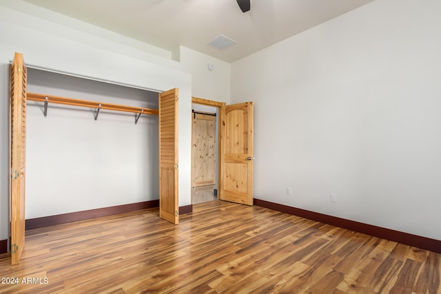 unfurnished bedroom featuring hardwood / wood-style flooring, ceiling fan, and a closet