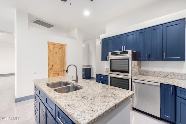 kitchen featuring blue cabinetry, stainless steel appliances, sink, and an island with sink