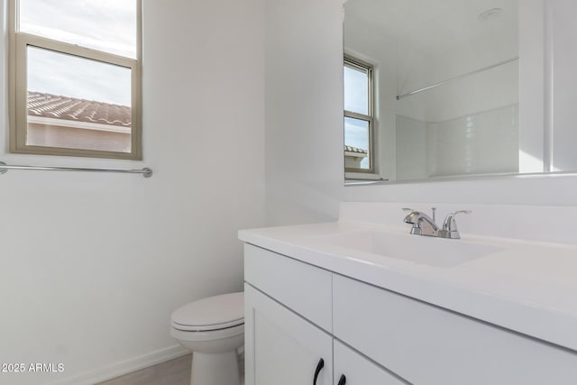 bathroom featuring vanity, a wealth of natural light, a shower, and toilet