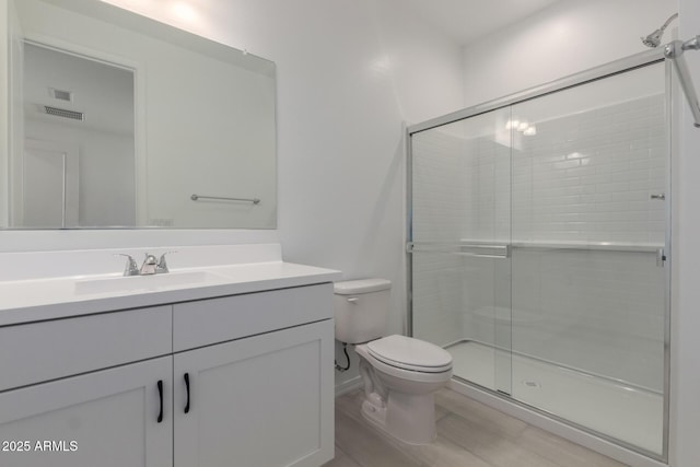 bathroom with toilet, vanity, a shower with door, and hardwood / wood-style floors