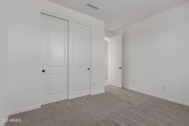 unfurnished bedroom with light carpet and a closet