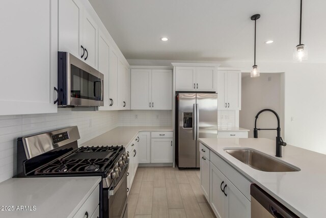 kitchen with appliances with stainless steel finishes, pendant lighting, sink, white cabinets, and backsplash