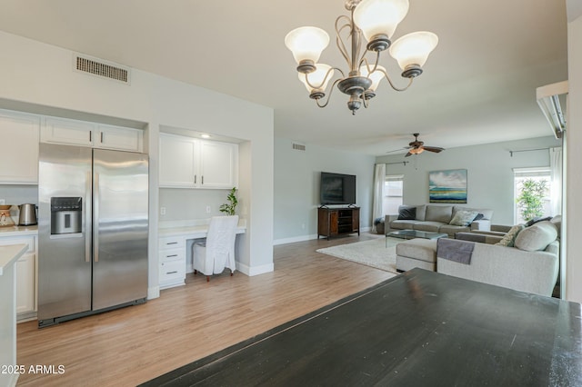 2218 E Anchor Dr, Gilbert, AZ 85234 - dining area featuring built in study area, light wood-style floors, visible vents, and ceiling fan with notable chandelier