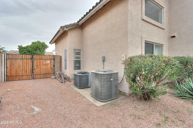 2218 E Anchor Dr, Gilbert, AZ 85234 - view of home's exterior with a gate, central AC unit, a tiled roof, and stucco siding