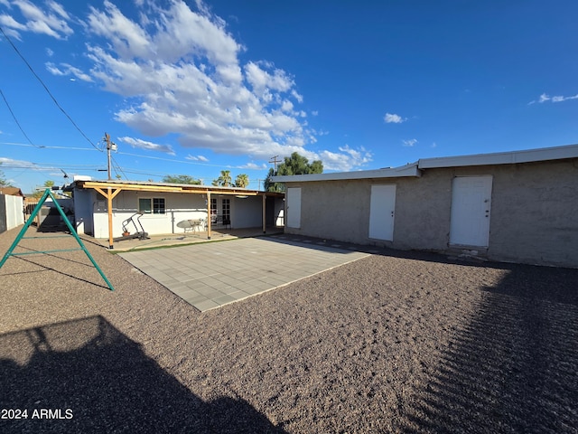 rear view of property with a patio area and a playground