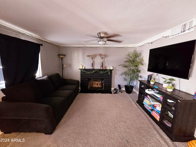 carpeted living room featuring a brick fireplace, a textured ceiling, and ceiling fan