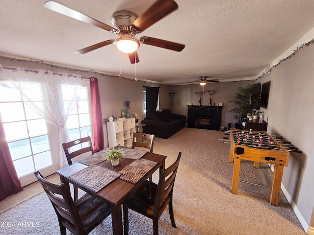 carpeted dining space featuring a textured ceiling, ceiling fan, and a fireplace