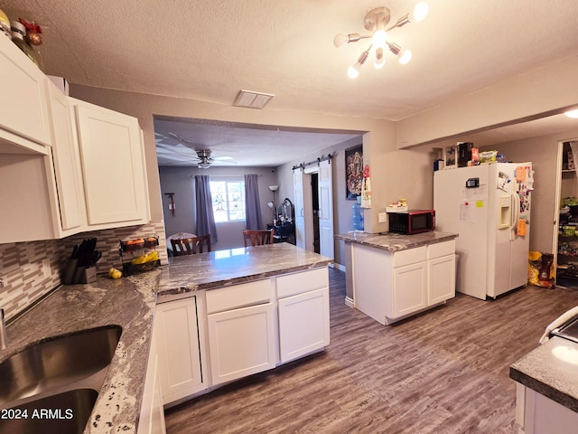 kitchen featuring white fridge with ice dispenser, a barn door, hardwood / wood-style flooring, sink, and white cabinetry