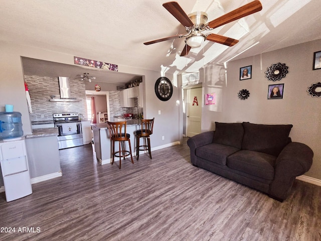 living room with a textured ceiling, ceiling fan, and dark wood-type flooring