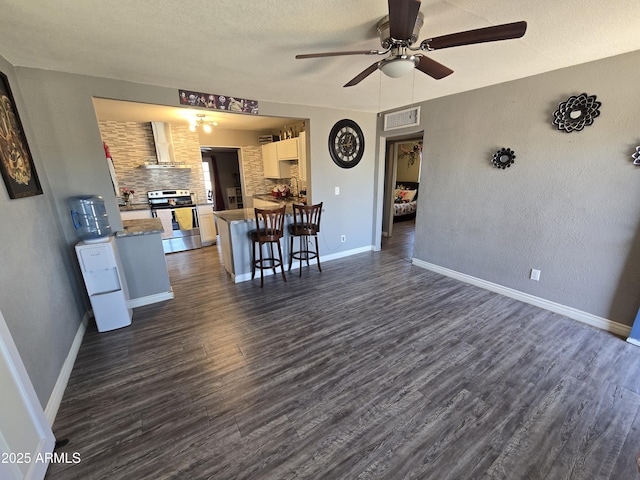 living room featuring ceiling fan, a textured ceiling, and dark hardwood / wood-style floors