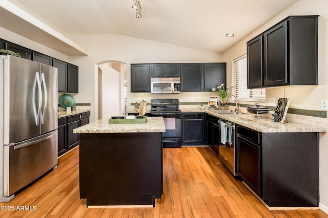 kitchen with light stone countertops, a kitchen island, light wood-type flooring, appliances with stainless steel finishes, and sink