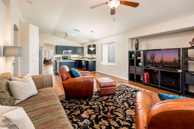 living room with ceiling fan, vaulted ceiling, and hardwood / wood-style floors